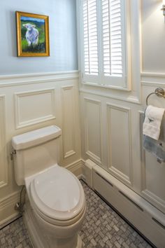 a white toilet sitting in a bathroom next to a window with shutters on it