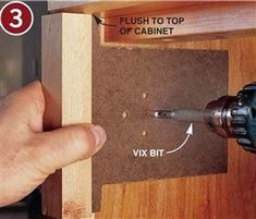 a person using a drill to fix a cabinet door