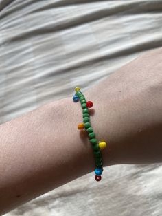 a person's arm with a bracelet made out of beads and colored beads on it