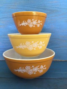 three yellow bowls sitting on top of each other in front of a blue wooden wall