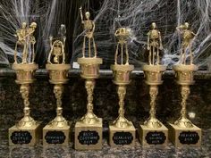 there are five golden trophies with skeletons on them