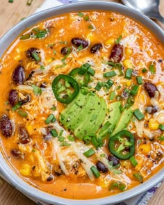 a bowl of mexican soup with tortilla chips and avocado on the side