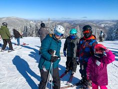 a group of people standing on top of a snow covered ski slope next to each other