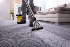 a man is cleaning the carpet with a vacuum