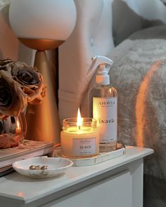 two candles are sitting on a table next to a mirror and vase with roses in it