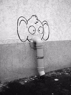 an elephant drawn on the side of a wall next to a fire hydrant with its trunk sticking out