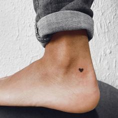 a small heart tattoo on the left side of the foot is shown in black and white