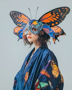 a woman wearing a butterfly mask and blue kimono with orange butterflies on her head