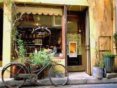 an old bicycle is parked in front of a flower shop with potted plants outside