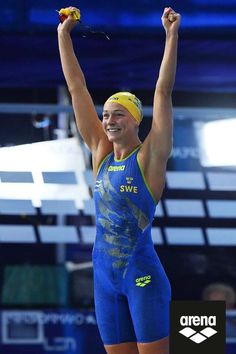 a woman in blue and yellow swimsuit holding up her arms