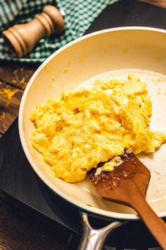 an omelet is being cooked in a pan with a wooden spatula next to it