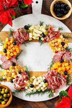 a platter filled with meats, cheese and olives on top of a wooden table