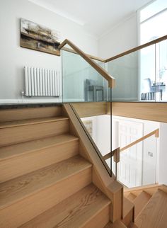 a wooden stair case with glass railing and handrail