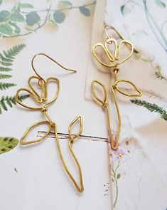 A  beautiful pair of hand shaped brass wire wild flower inspired earrings Based on a simple outline drawing I did of a wild flower, I used wire to replicate its lines and shapes.  These earrings are delicate, lightweight and so easy to wear They are made from gold brass wire, and are hung from gold plated french hooks They are minimalist and graceful The measure approximately 7cm from the top of the hook to the bottom of the stem Simple Shapes Design, Handmade Gold Flower Earrings For Spring, Gold Whimsical Flower-shaped Earrings, Nature-inspired Gold Wire Wrapped Earrings, Whimsical Gold Flower Earrings, Whimsical Gold Flower-shaped Earrings, Whimsical Gold Wire Wrapped Earrings, Nature-inspired Gold Flower Earrings With Ear Wire, Gold Nature-inspired Flower Earrings