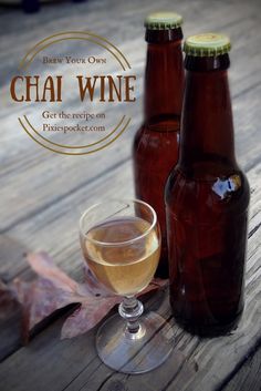 two bottles and a glass filled with white wine on a wooden table next to leaves