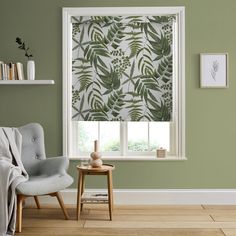 a living room with green walls and a window covered in blinds that have leaves printed on them