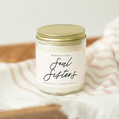 a jar of candles sitting on top of a wooden tray next to a striped towel