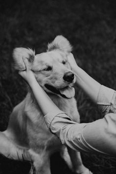 a woman petting a dog on the back of it's head in black and white