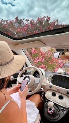 a woman sitting in the driver's seat of a car looking at her cell phone