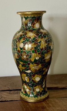 a vase sitting on top of a wooden table next to a white wall and wood floor