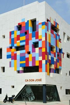 a building with colorful blocks on the side and motorcycle parked next to it in front