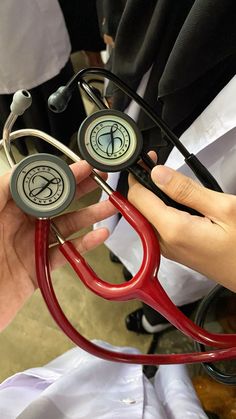 a person holding a red stethoscope in their hand with other medical equipment nearby