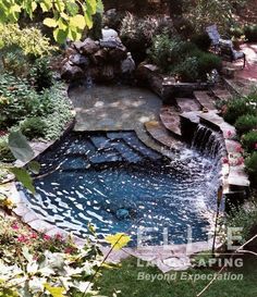 an outdoor swimming pool surrounded by trees and flowers in the middle of a garden area