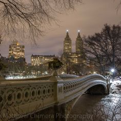 the city lights shine brightly in the distance as it stands over a river and bridge