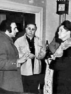 an old black and white photo of people standing in front of a door talking to each other