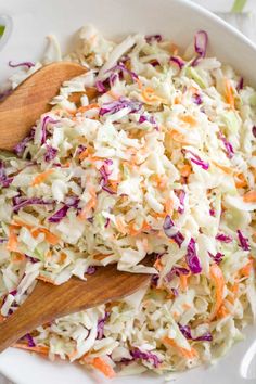 coleslaw salad in a white bowl with wooden spoons on the side, ready to be eaten