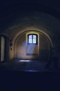 an empty room with a window and light coming in from the outside, on a dark background