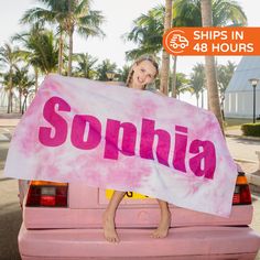 a woman standing in the back of a pink car holding a sign that says,