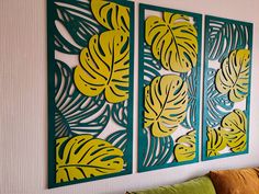 two green and yellow wall hangings on a white wall next to a brown couch