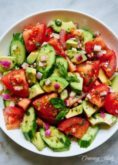 a white bowl filled with cucumber and tomato salad