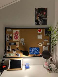 a desk with a laptop, lamp and pictures on the wall