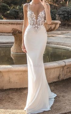 a woman in a wedding dress standing next to a fountain with her hand on her hip