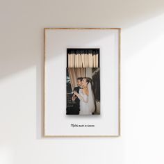 a photo frame hanging on the wall with matches in it and a bride and groom kissing