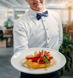 a man in a bow tie holding a plate with food on it