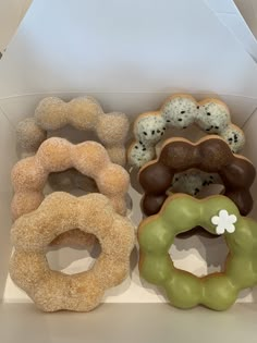 four donuts in a box with different toppings on them, one is green and the other is brown