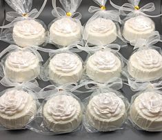 twelve white frosted cupcakes wrapped in clear cellophane and tied with bows