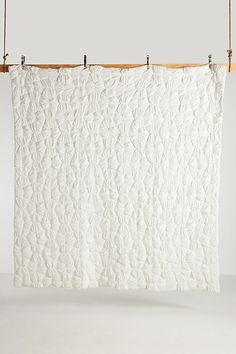 a white quilt hanging from a wooden hanger