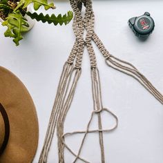 a hat, rope and other items on a white table with a plant in the background