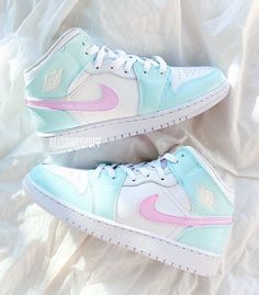 a pair of white and pink sneakers on top of a bed