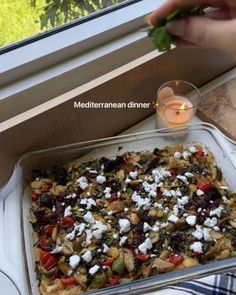 a person is holding a piece of food in front of a window with the words mediterranean dinner on it