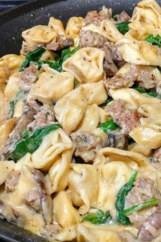 a skillet filled with pasta, meat and spinach