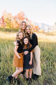 three girls hugging each other in the grass