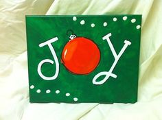 a green box with a red ornament on it and the word joy written in white