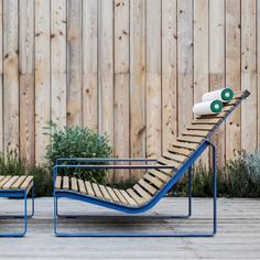 two lounge chairs sitting next to each other in front of a wooden fence