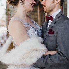 a man and woman dressed in formal wear standing next to each other with fur stolers on