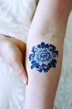 a woman's arm with a tattoo on it that has blue and white designs